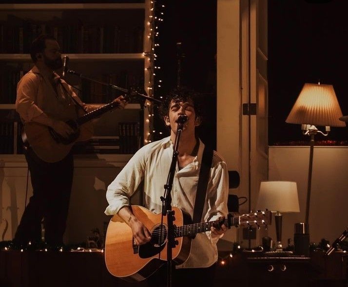 two men are playing guitars and singing into microphones in front of a christmas tree