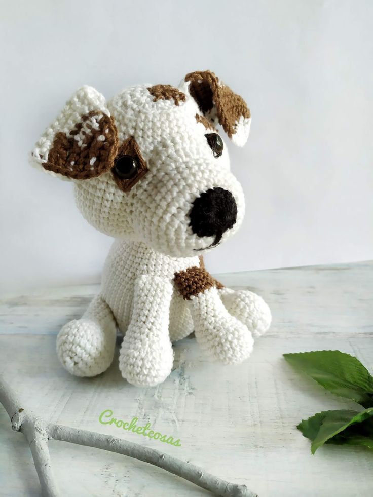 a crocheted dog sitting on top of a table next to a green plant