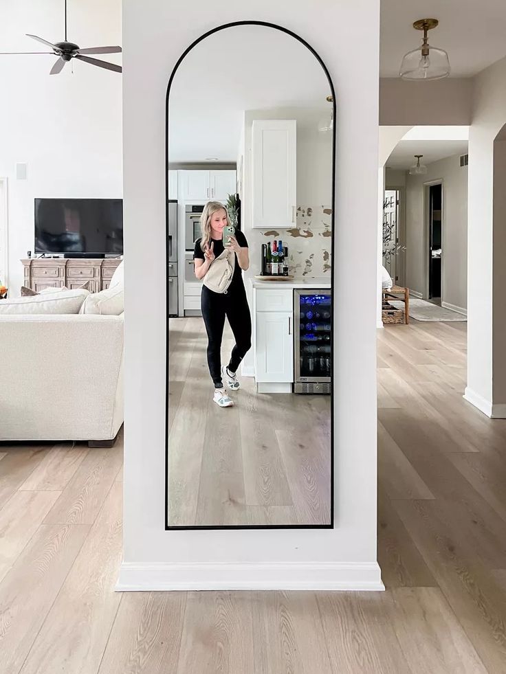 a woman is taking a selfie in the mirror while standing on a hardwood floor