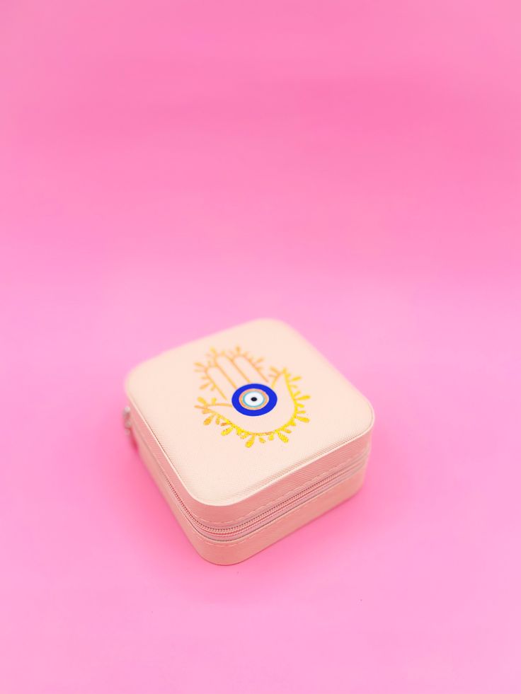 a pink and white lunch box with an evil eye design on it's lid