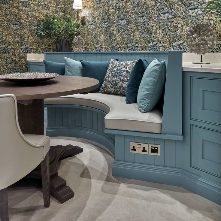 a kitchen with blue walls and white chairs around a round wooden table in the center