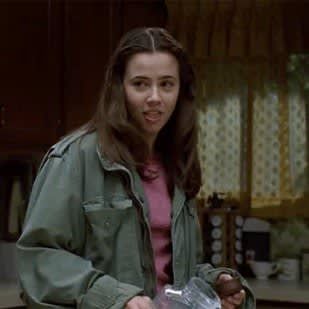 a woman standing in a kitchen holding a plastic container with something in it's hand