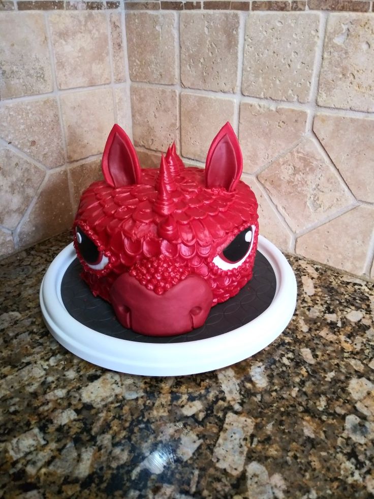 a red dragon head cake sitting on top of a counter next to a tile wall