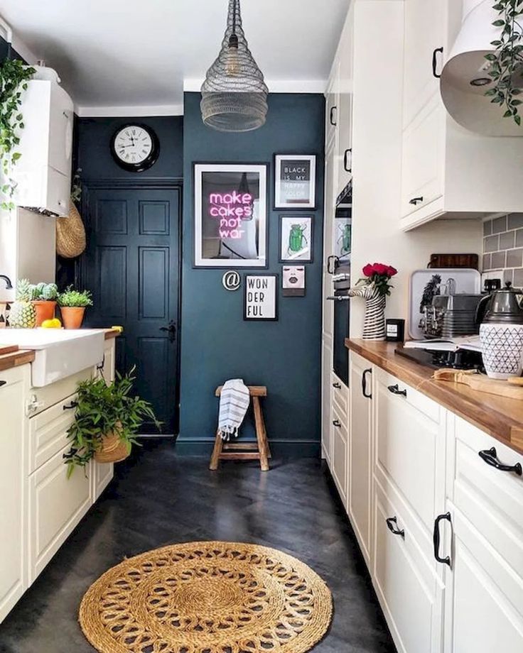 a kitchen with blue walls and white cabinets, an area rug and potted plants