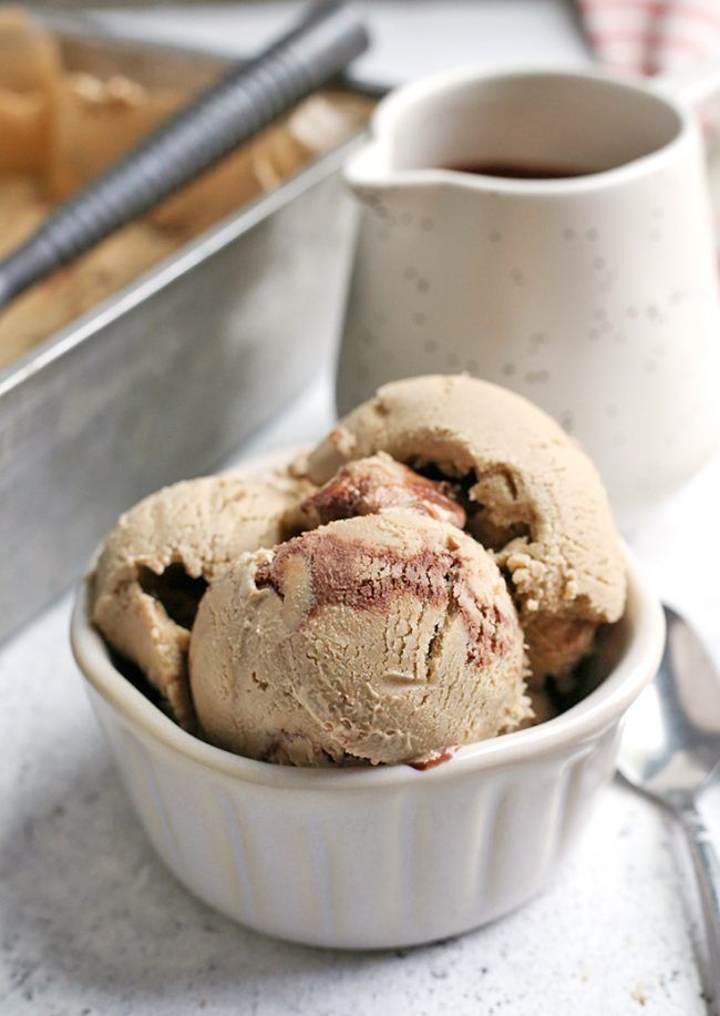 two scoops of ice cream sit in a bowl next to a cup and spoon