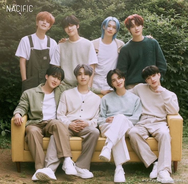 the group of young men are posing for a photo on a yellow couch in front of some bushes