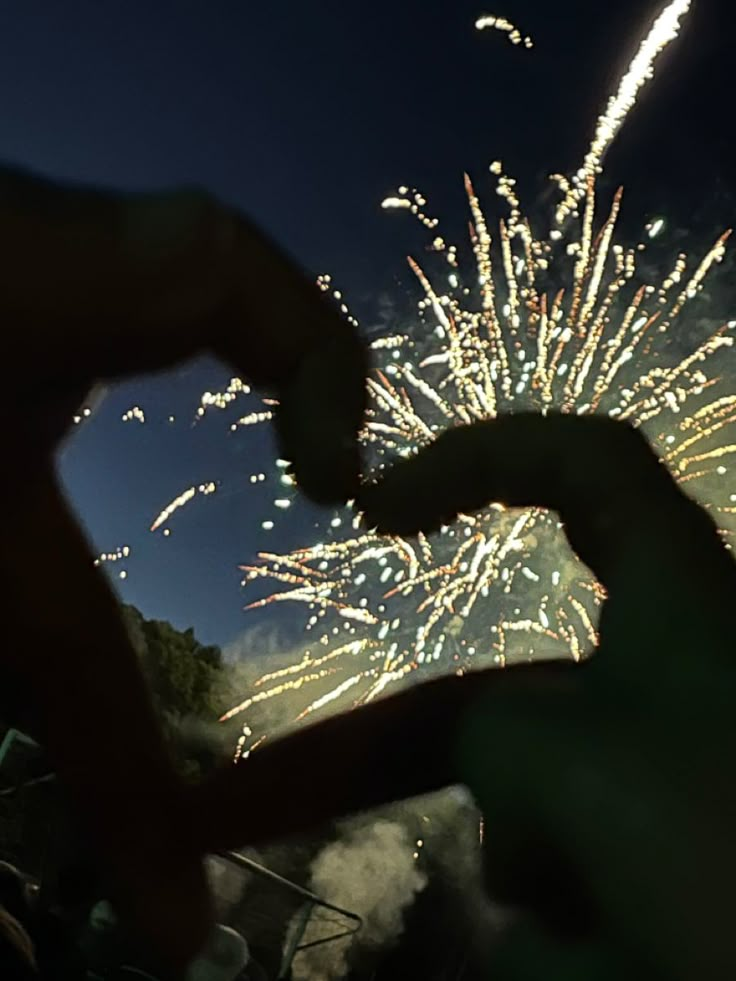 fireworks are lit up in the night sky with their silhouettes touching each other's hands