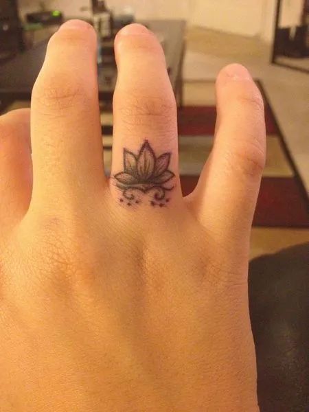 a person's hand with a small tattoo on the middle finger, and a flower in the middle