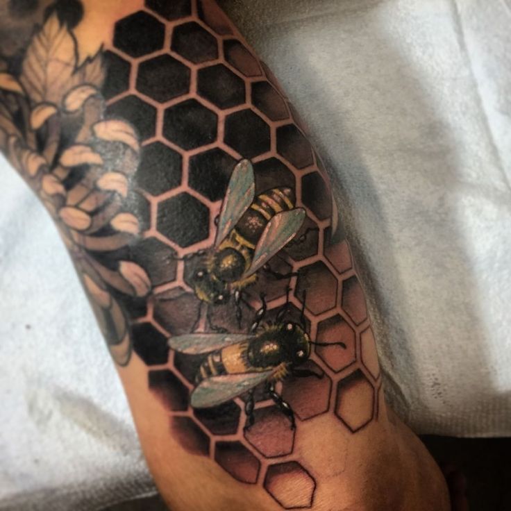 a man with a tattoo on his arm has bees and honeycombs on it