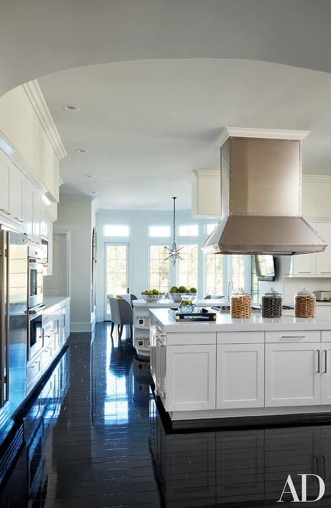 a large kitchen with white cabinets and black flooring