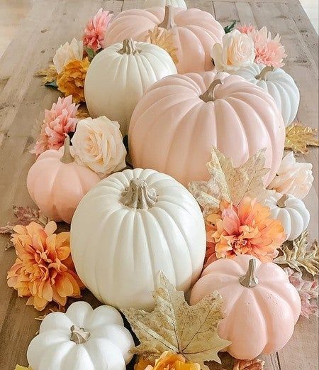 several white pumpkins and flowers on a wooden table