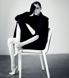 a black and white photo of a woman sitting on a chair with her legs crossed