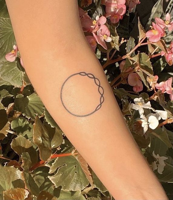 a woman's arm with a tattoo on it and flowers in the back ground