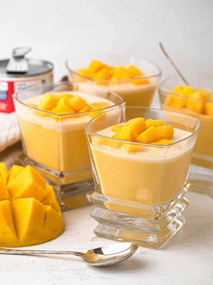 mango pudding in small glass bowls with spoons and canisters next to them