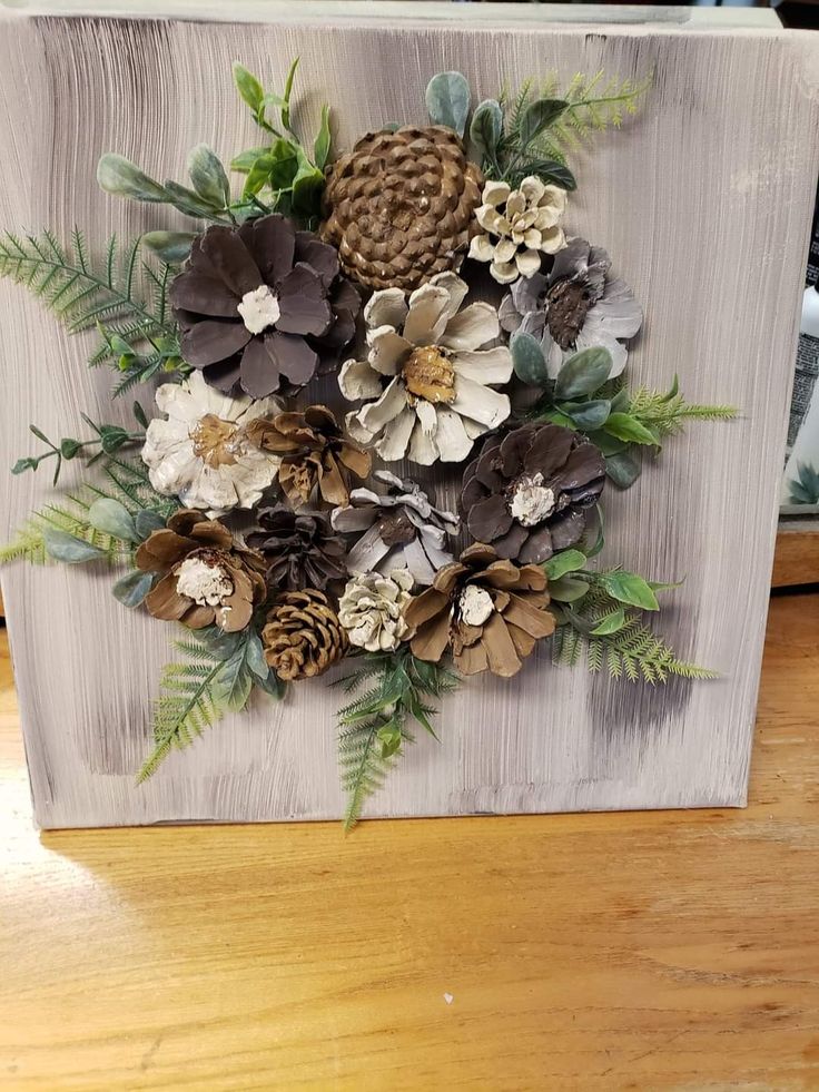 a painting with pine cones, flowers and leaves painted on the side of a wooden board