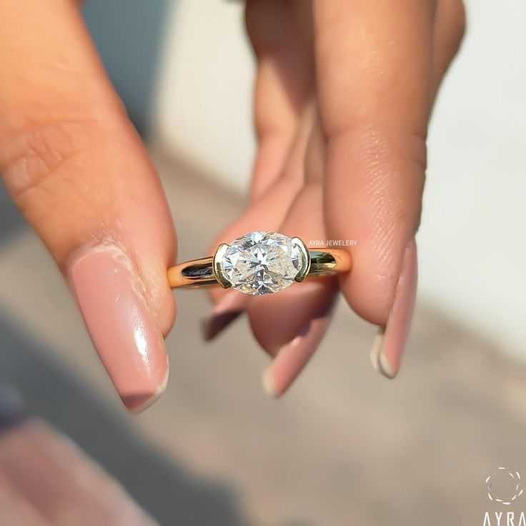 a woman's hand holding an engagement ring with a diamond on the middle finger