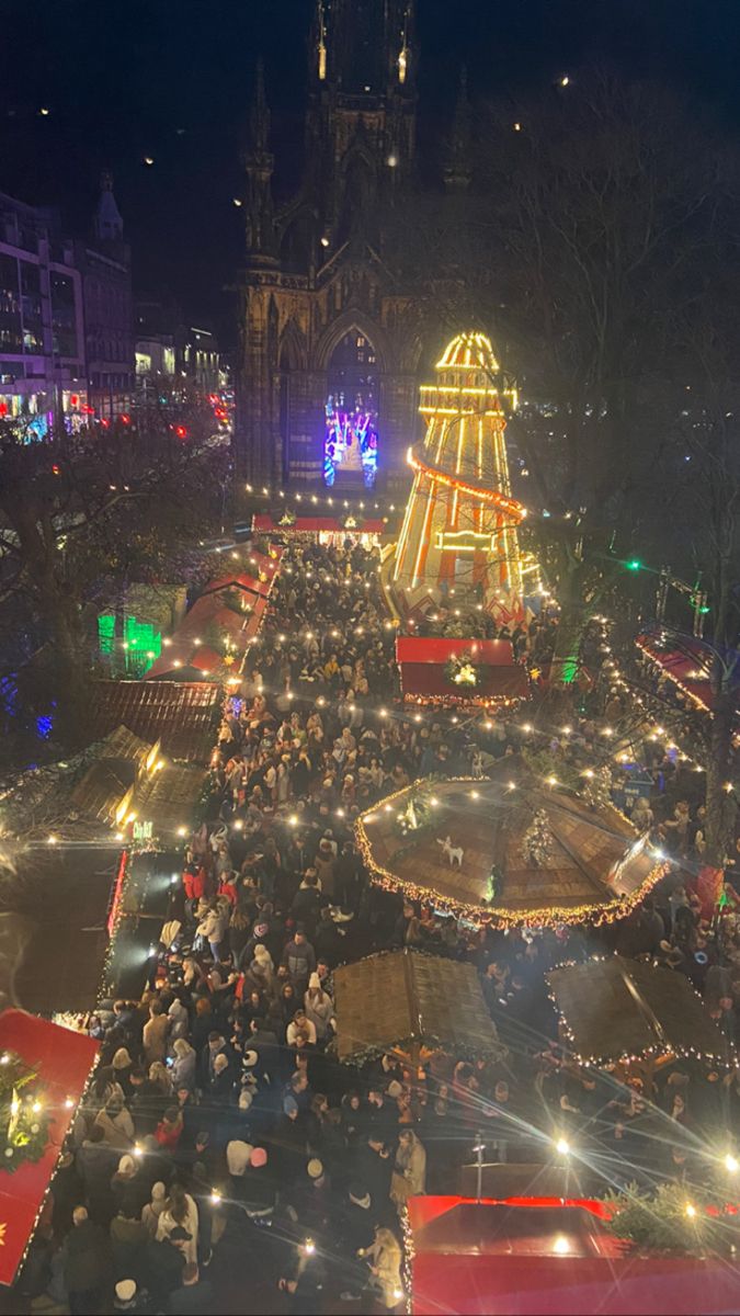 a large group of people standing around a christmas tree in the middle of a city