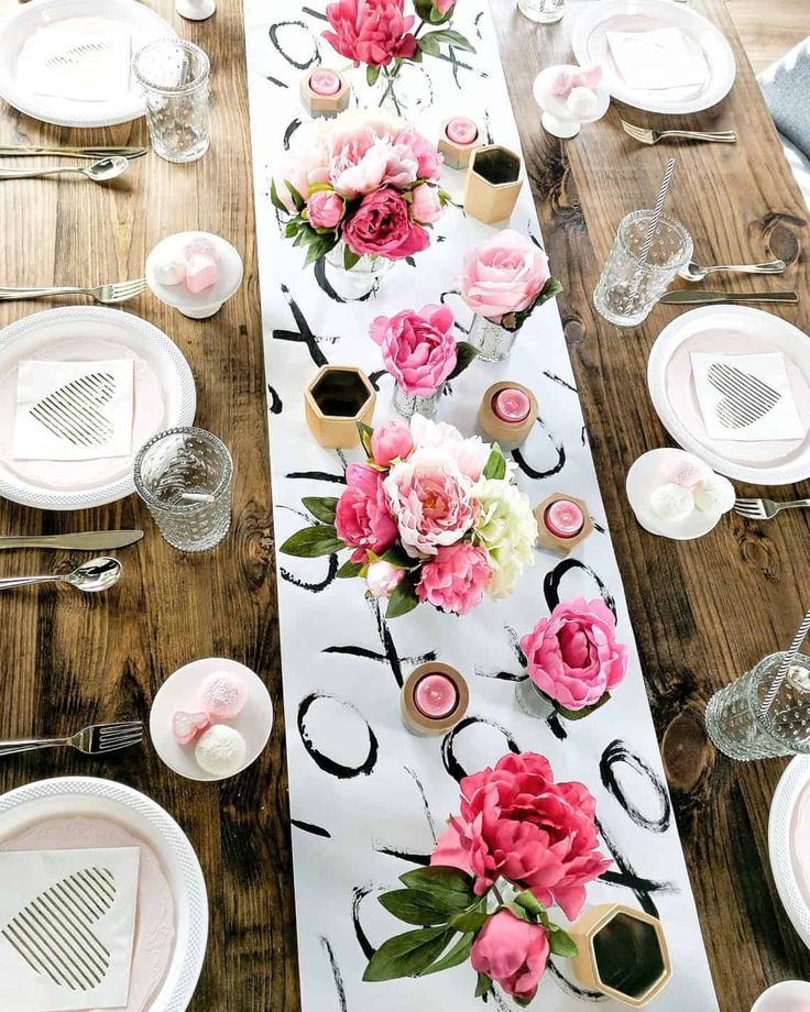 the table is set with white plates and pink flowers