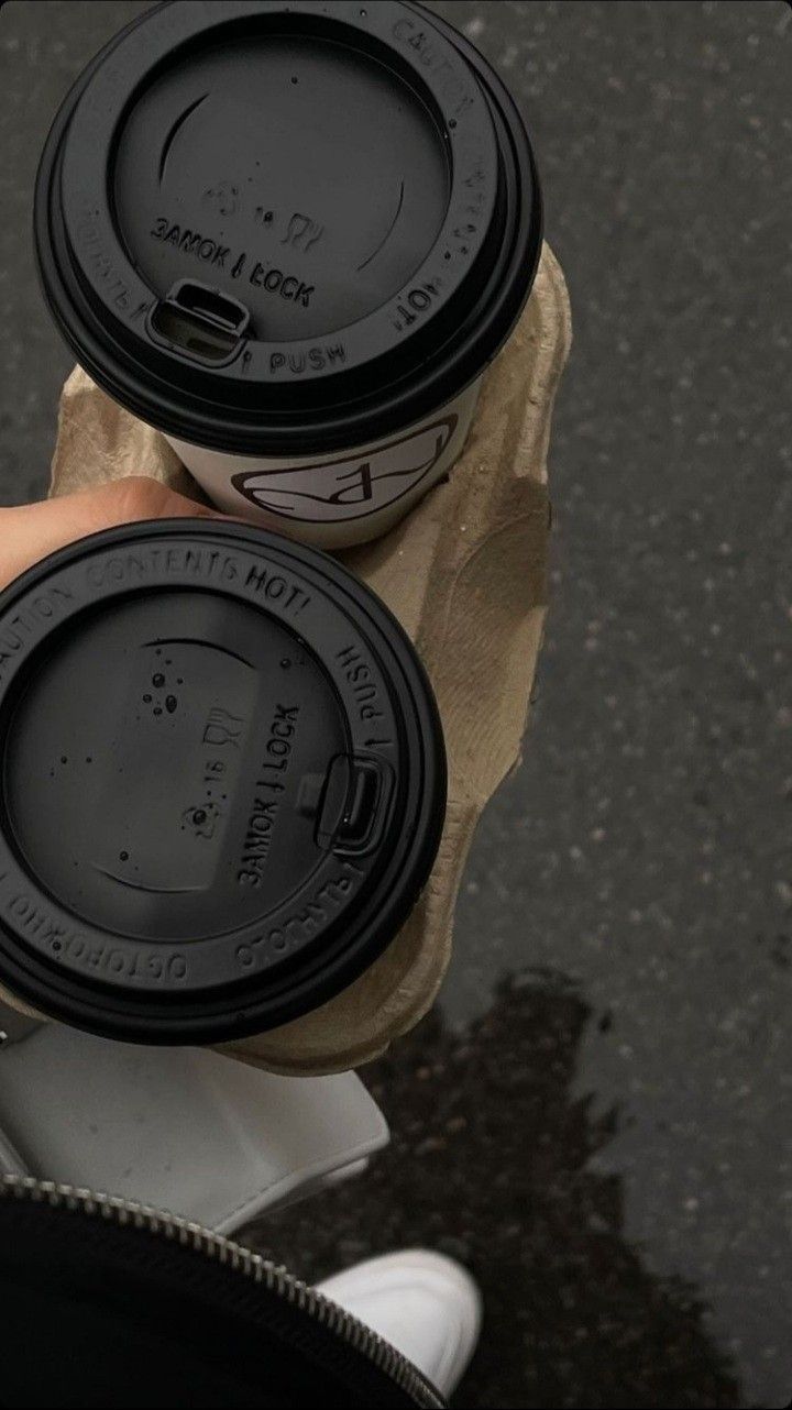 two coffee cups sitting on top of each other in front of a person's hand