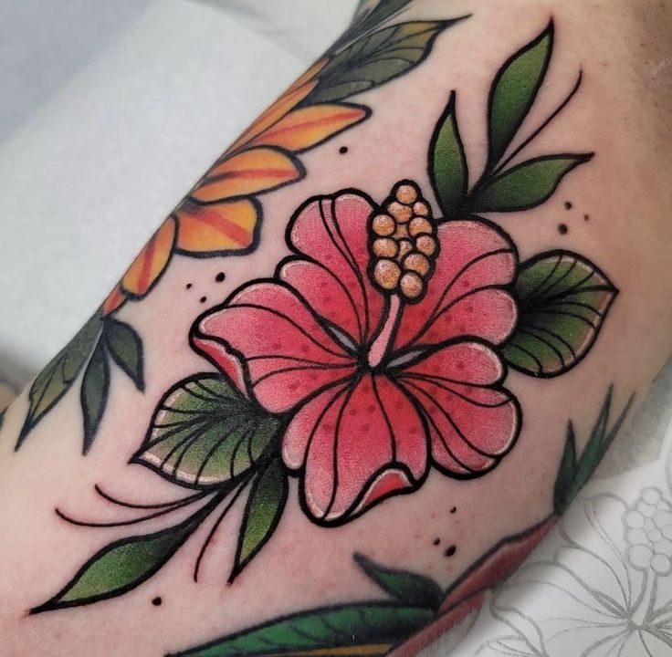 a flower tattoo on the arm with leaves and flowers around it's center piece