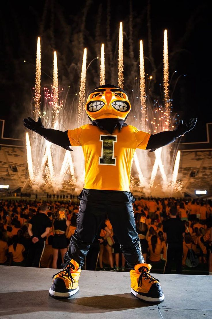 a person dressed in an orange and black football uniform standing on a stage with fireworks behind them