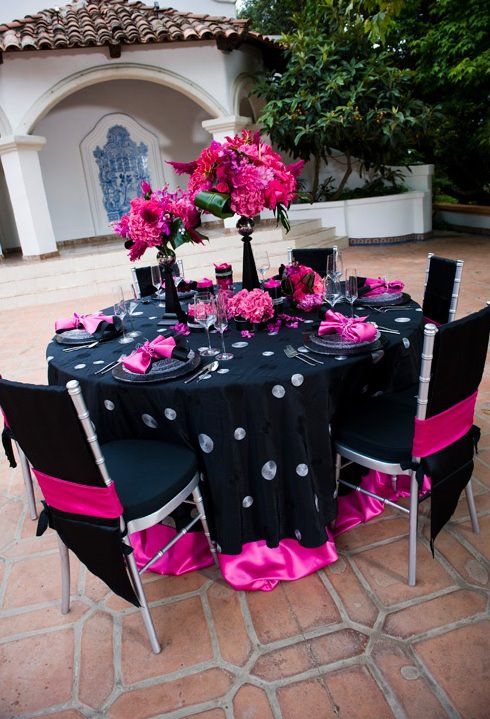 the table is set with black and pink decorations