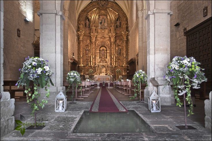 the interior of a church with flowers and candles on the pews in front of it