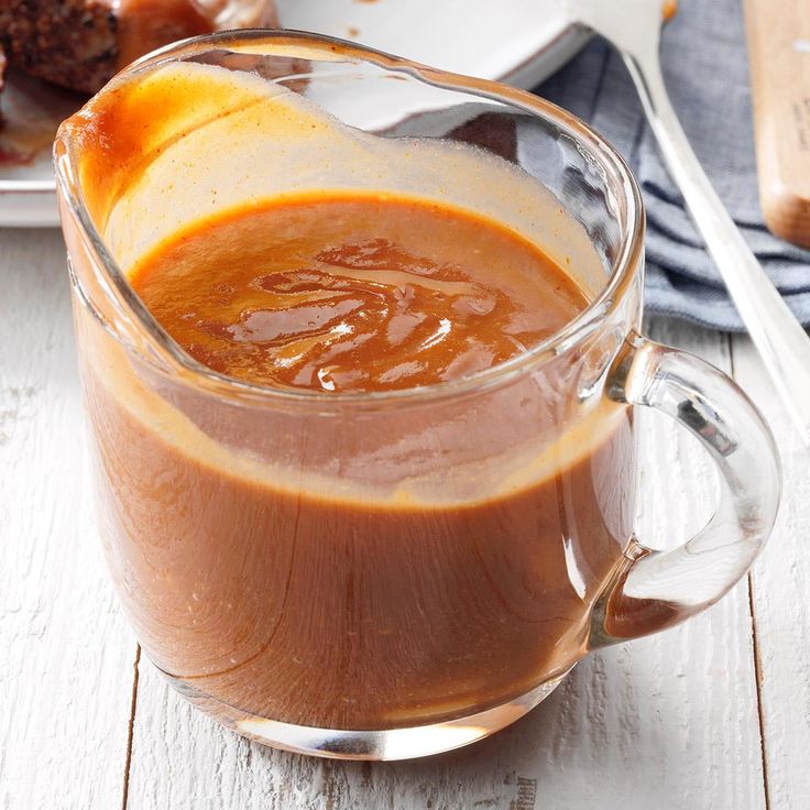 a glass mug filled with caramel sauce next to donuts on a plate and napkin