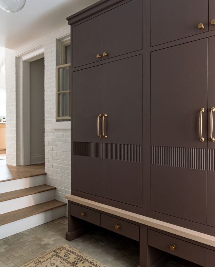 a large brown cabinet sitting in the middle of a living room next to a stair case