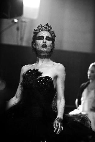 a woman in a black dress with feathers on her head