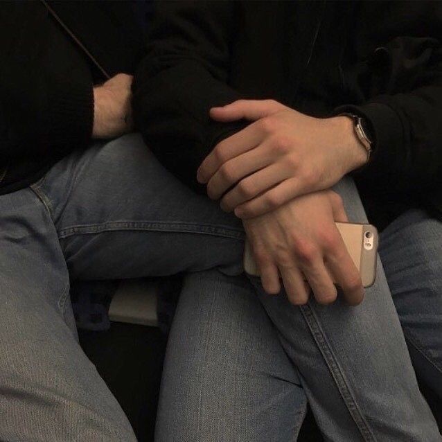 two people sitting next to each other with their hands resting on the back of one another