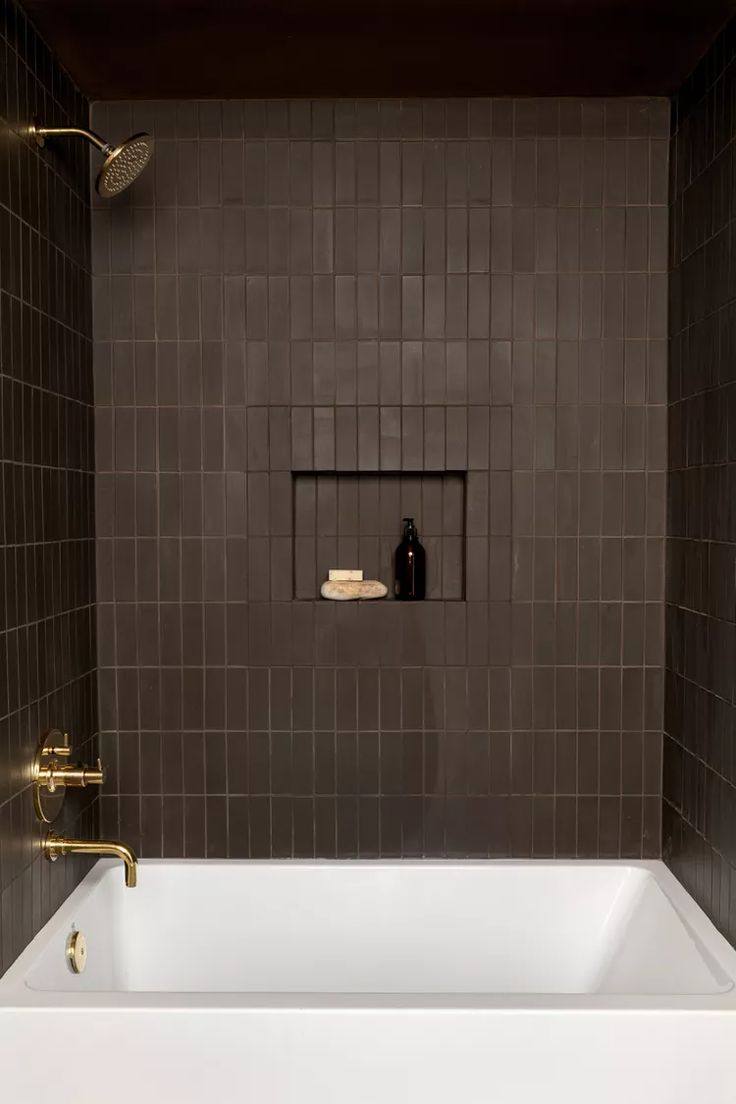 a white bath tub sitting inside of a bathroom next to a wall mounted soap dispenser