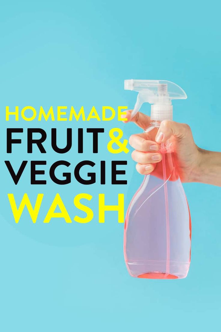 a hand holding a bottle of fruit and veggie wash on a blue background