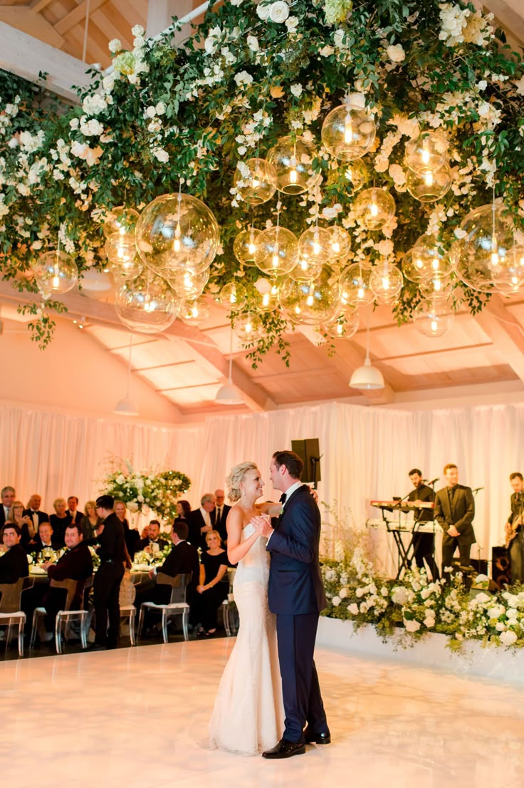 a bride and groom sharing their first dance at the wedding reception in front of an audience