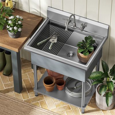 a kitchen sink with pots and plants on the side