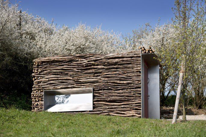 a building made out of sticks and grass with trees in the backgroung