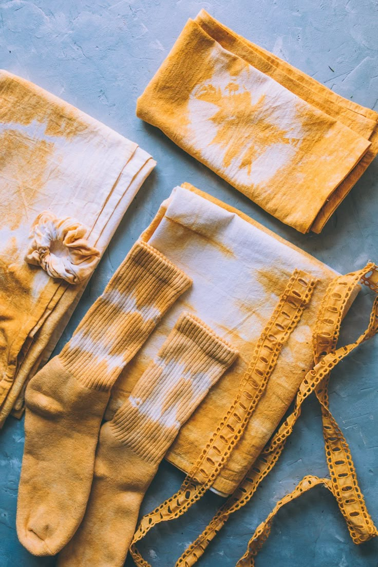 several pairs of yellow socks and ties laid out on a blue surface with stains all over them