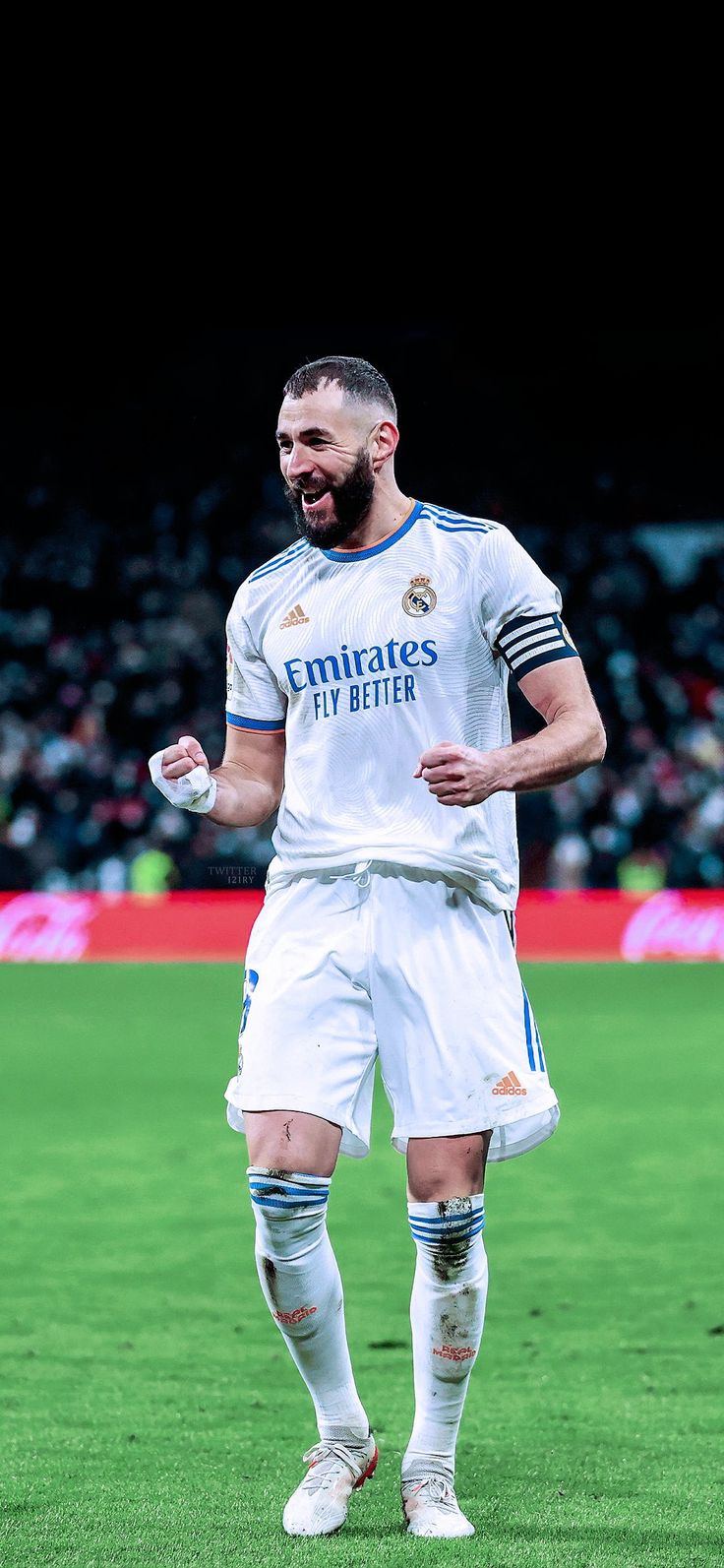 a man in white soccer uniform standing on the field with his hands out and mouth open