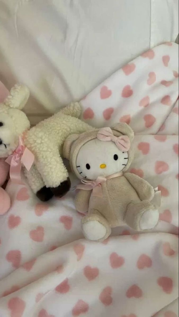 two stuffed animals laying on top of a bed covered in pink and white polka dots