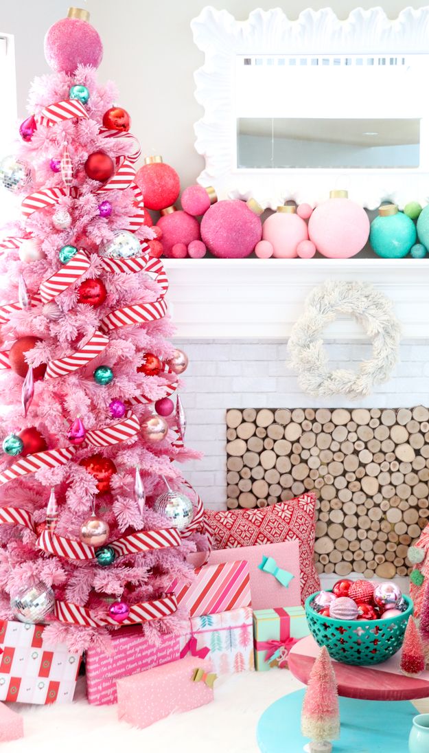 a pink christmas tree in front of a fireplace with presents under it and colorful ornaments on the mantle