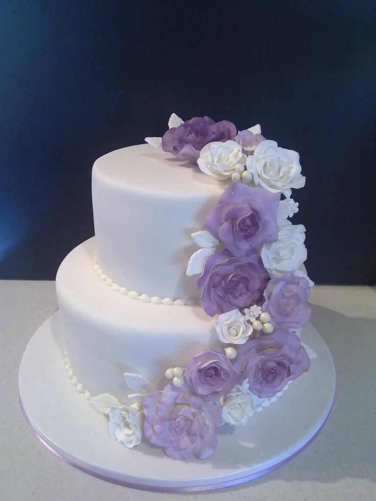 a three tiered white cake with purple and white flowers