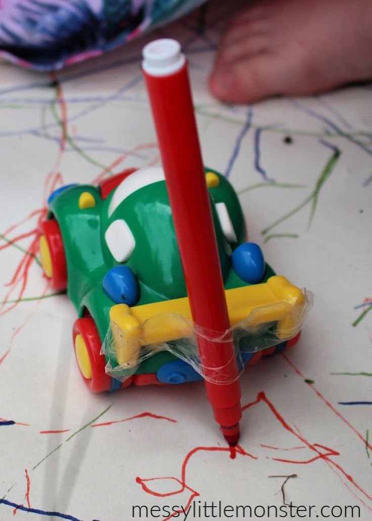 a red pen is next to a green toy car on a table with colored crayons