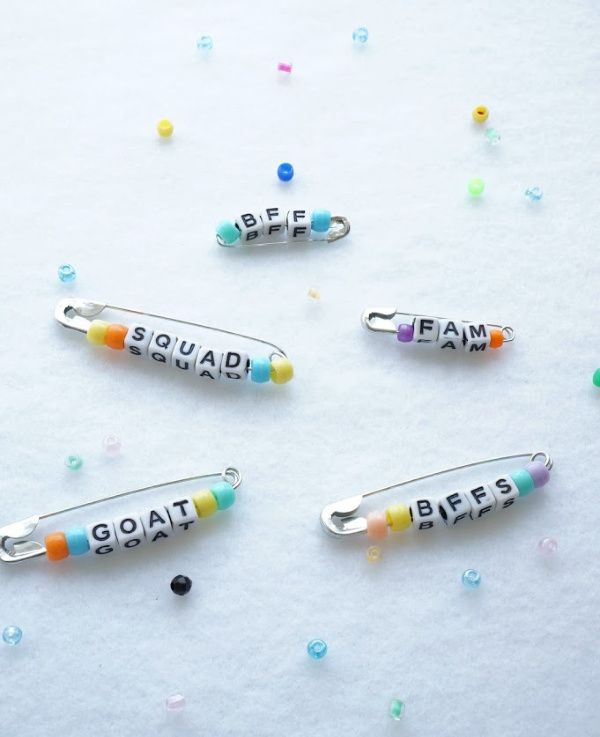 three pins with words on them sitting next to confetti sprinkles