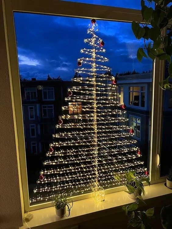 a lit up christmas tree sitting on top of a window sill