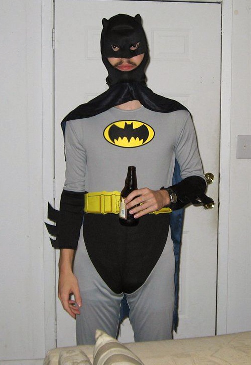 a man dressed as batman holding a beer in his hand and the caption reads, the longer you look