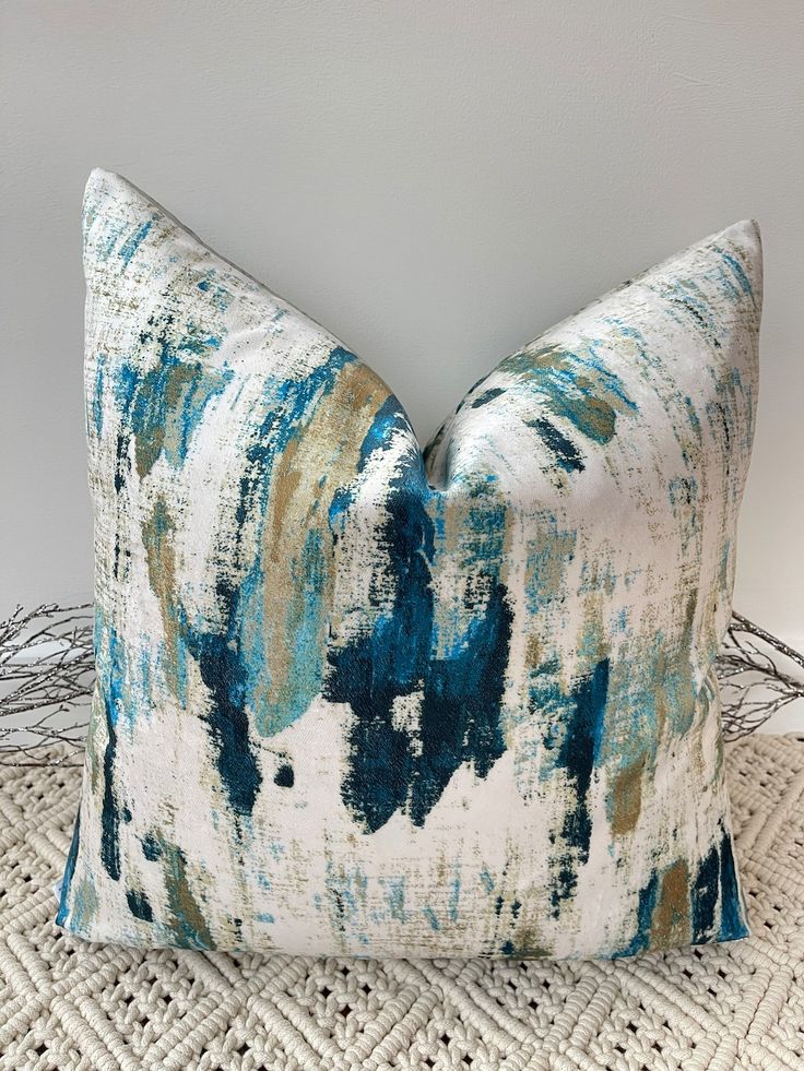 a blue and white pillow sitting on top of a bed