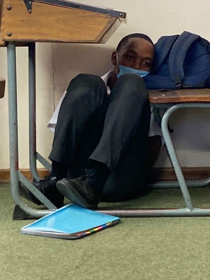 a man sitting in a chair with his back to the camera and covering his mouth