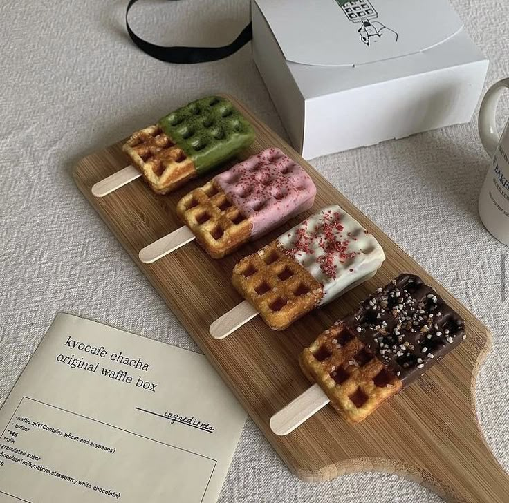 several waffles are on a wooden plate next to a coffee cup and box