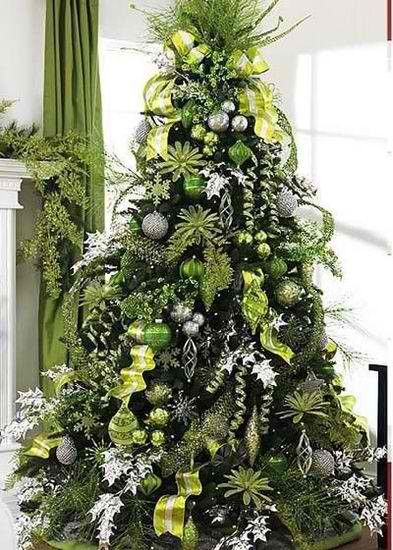 a decorated christmas tree in a living room with green and silver ornaments on the top