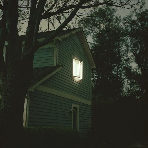 a house that is lit up by the light of a window on a dark night